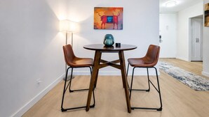 A modern dining area with a round table, two chairs, a lamp, and a painting on the wall. - Spacious Apt in Murray Hill (New York, NY)