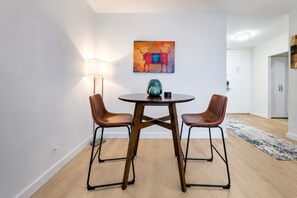 A modern dining area with a round table, two chairs, a lamp, and a painting on the wall. - Spacious Apt in Murray Hill (New York, NY)