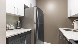 A modern kitchen with a stainless steel refrigerator, white cabinets, and a light-colored backsplash. - Spacious Apt in Murray Hill (New York, NY)