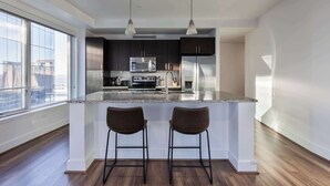 Una cocina moderna con una isla grande, electrodomésticos de acero inoxidable y vistas a la ciudad.
