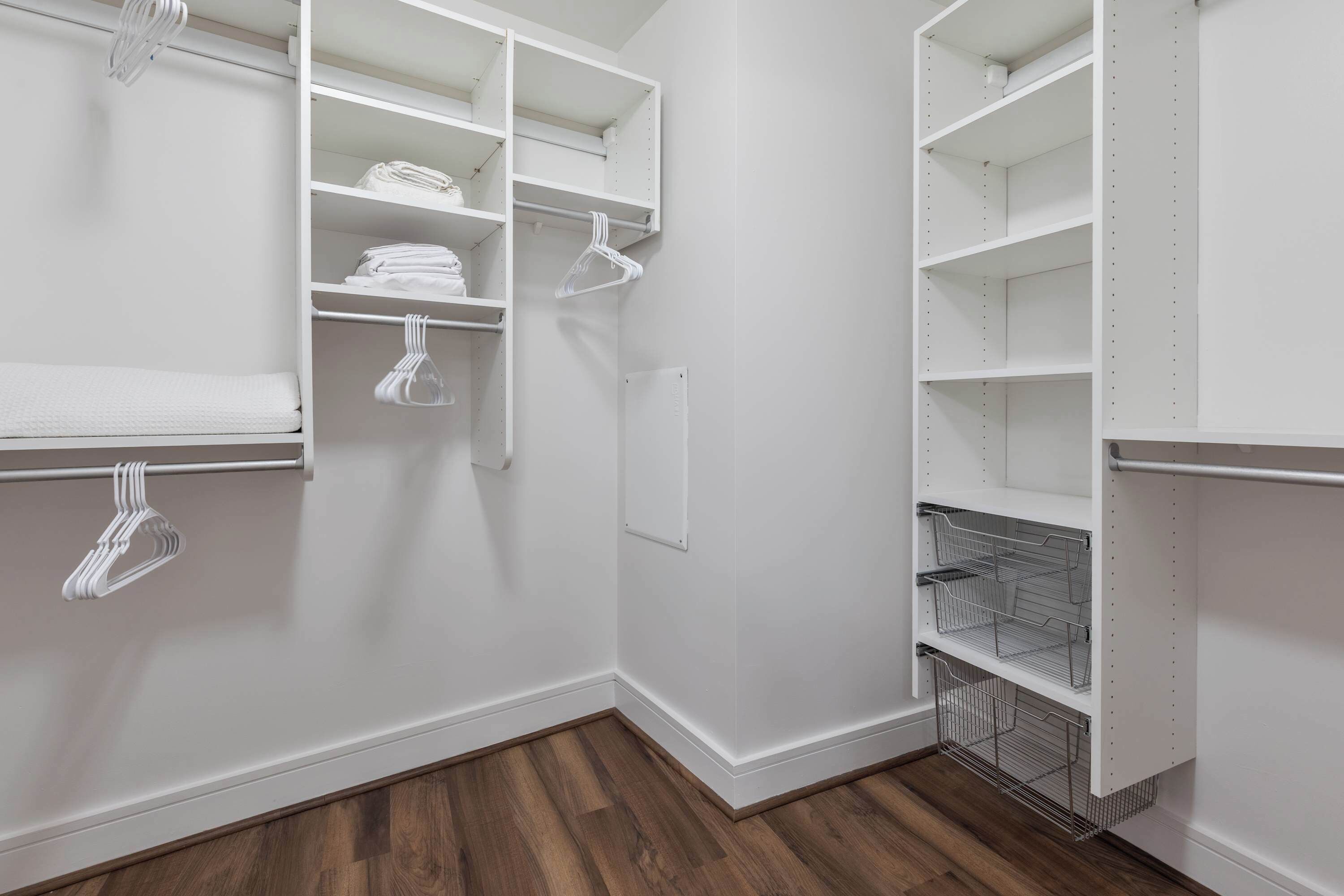 A walk-in closet with open shelves, a metal rack, and a white door.