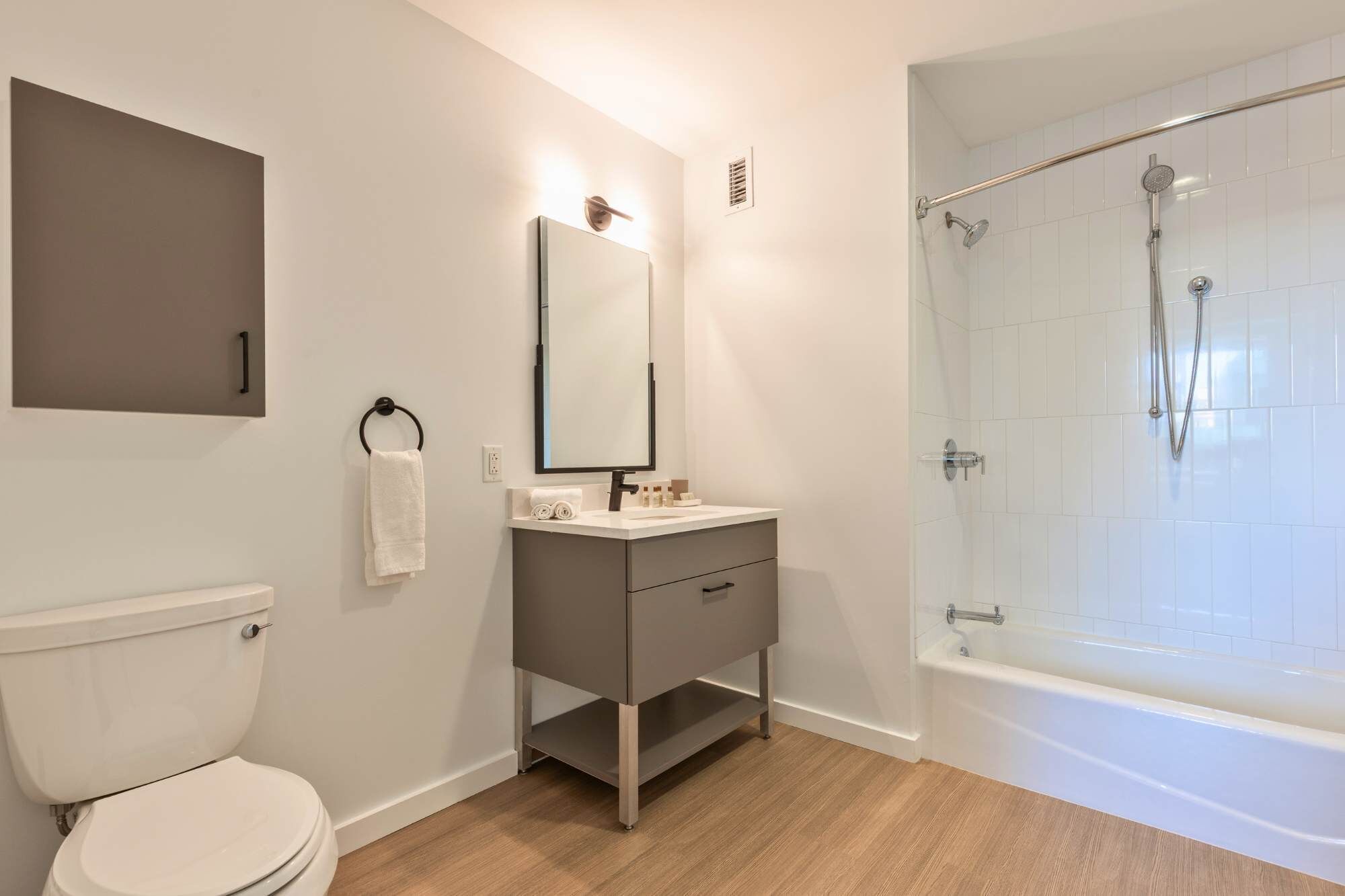 Een moderne badkamer met toilet, wastafel, spiegel en douchecabine.