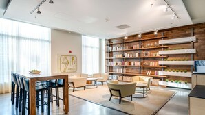 Een moderne kantoorruimte met een houten boekenkast, een zithoek met stoelen en een groot raam.