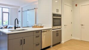 Een moderne keuken met een inbouwoven, roestvrijstalen kastjes en een groot raam.