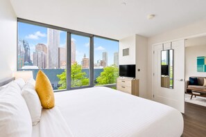 A modern hotel room with a large bed, a TV, a dresser, and a city view. - Lux Apt with Pool in Boston Seaport (Boston, MA)