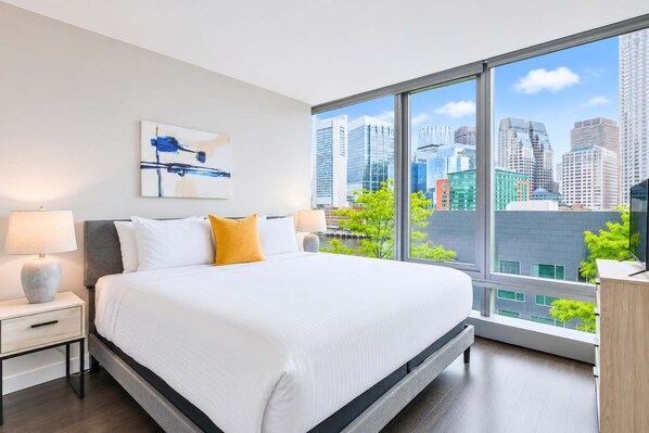 Una habitación de hotel moderna con una cama grande, vistas a la ciudad y una decoración minimalista.