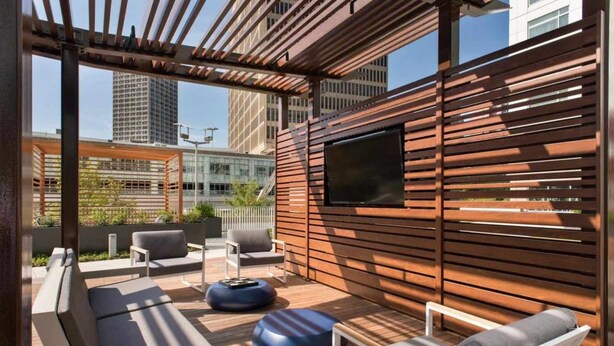 An outdoor seating area with wooden slats, a flat-screen TV, and modern furniture. - Luxury Apt On Canal in Cambridge (Cambridge, MA)