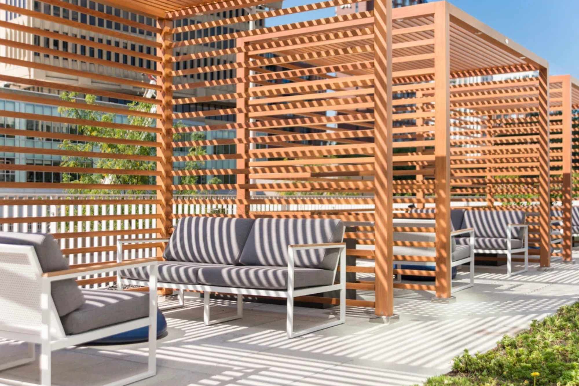 Outdoor seating areas with wooden lattice structures and white metal frames.