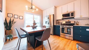 Una cocina moderna con comedor, piso de madera y un ventanal grande.