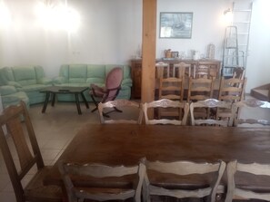 Un coin repas avec une table et des chaises en bois, un canapé vert et un meuble en bois.