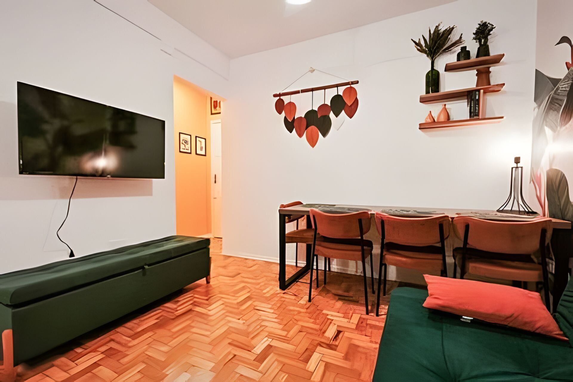 Una sala de estar moderna con un televisor de pantalla plana, un sofá, una mesa de comedor con sillas y un suelo con estampado tipo espiga.