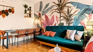 A modern living room with a teal sofa, wooden dining table, and chairs. - Apartamento Cheio de Estilo perto da FEI (São Bernardo do Campo)