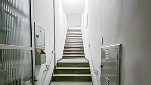 A narrow hallway with a staircase leading to a door at the end. - Apartamento Cheio de Estilo perto da FEI (São Bernardo do Campo)