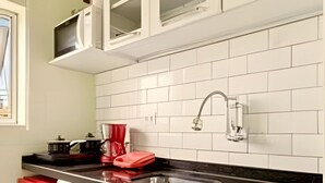 A kitchen with white cabinets, a black countertop, and a red appliance. - Apartamento Cheio de Estilo perto da FEI (São Bernardo do Campo)