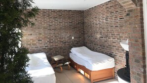 A corner room with a brick wall, a wooden bed, a small stool, and a white ceiling. - Serene Countryside Apartment in Gjesdal, Norway (Gjesdal)