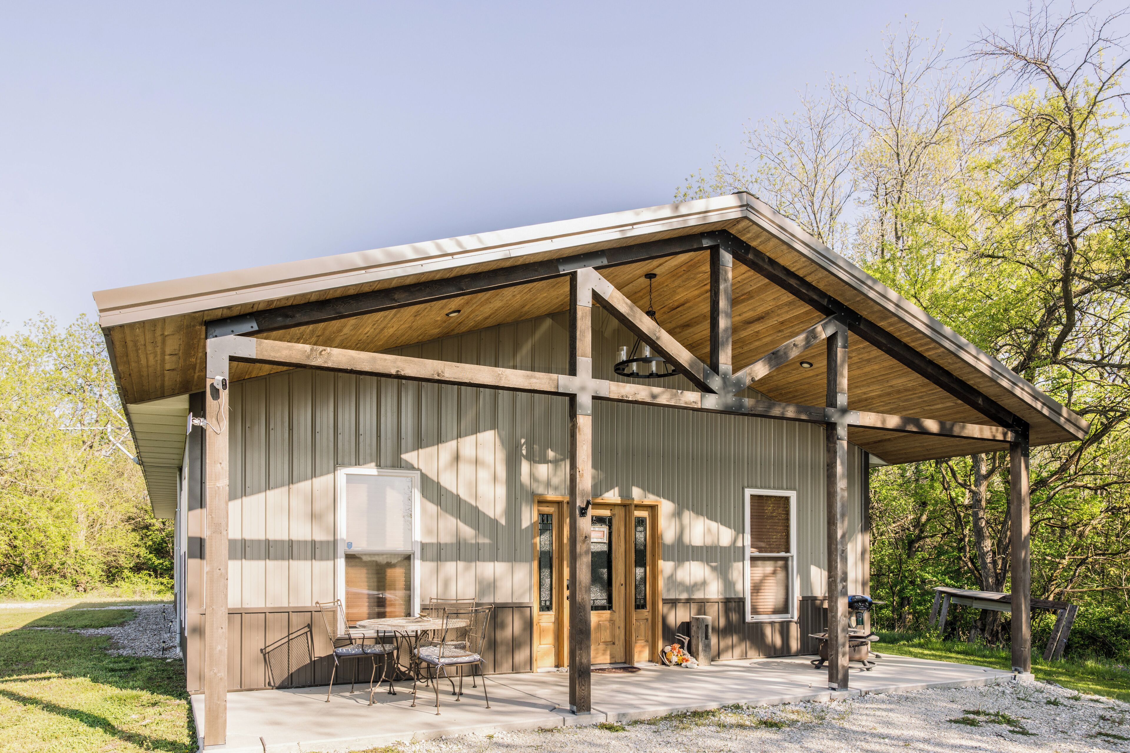 A rustic building with a covered porch, wooden beams, and a small outdoor seating area.