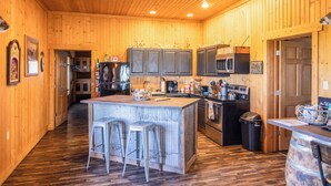 Un interior de madera con una isla de cocina, taburetes de bar y un barril grande.