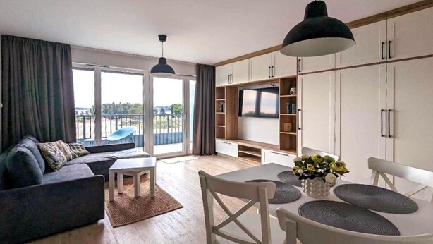 Een moderne woonkamer met een bank, salontafel en een eethoek met stoelen en een tafel.