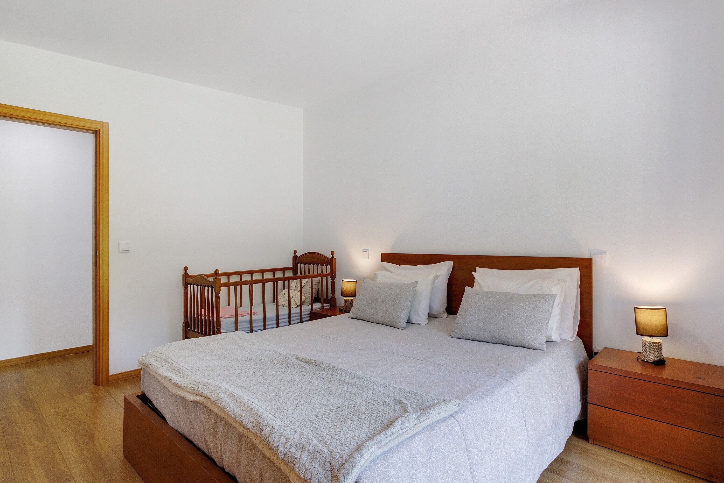Un dormitorio con una cama de madera, mesitas de noche y un buró.
