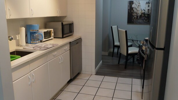 A compact kitchen with white cabinets, a coffee maker, a microwave, and a dishwasher.