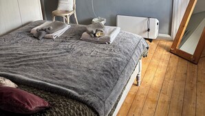 Makuuhuoneessa on sänky, yöpöytä, peili, ikkuna, jossa on verhot, ja seinälle kiinnitetty hylly.