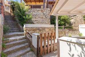 Una escalera de piedra que lleva a una terraza de madera con barandilla blanca.
