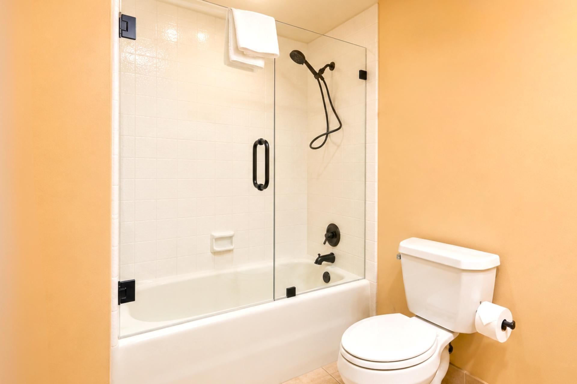 Une salle de bain avec une baignoire blanche, des toilettes et une douche séparée par une paroi de verre.