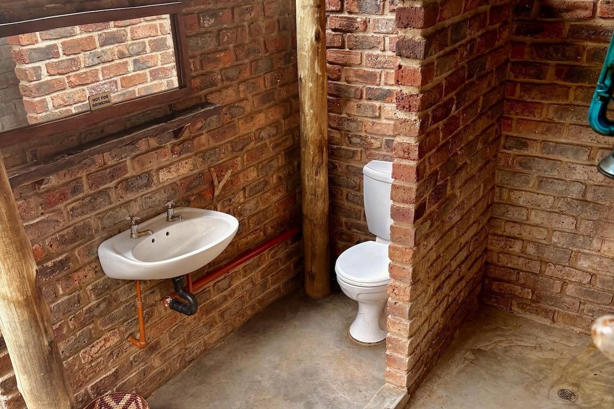 A small, enclosed bathroom with a sink, toilet, and a 'NOT FOR DRINKING' sign.