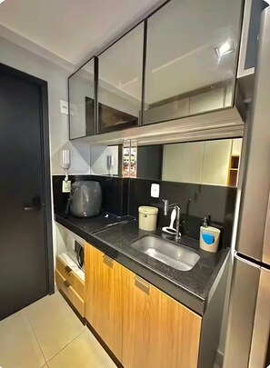 Eine moderne Küche mit schwarzem Arbeitsplatz, Edelstahlgeräten und Holzschränken.