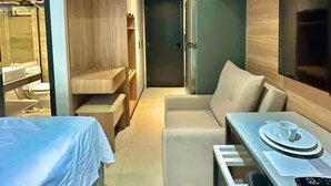 Une chambre d’hôtel moderne équipée d’un lit, d’un canapé, d’une table à manger, d’un téléviseur intégré et d’une salle de bain séparée.