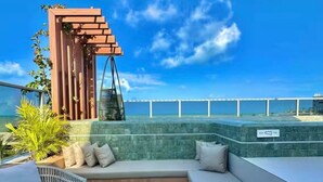 Une terrasse sur le toit dotée d’une pergola en bois, d’un espace salon et offrant une vue sur l’océan.