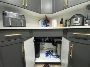A kitchen with a built-in washing machine, a coffee maker, and a rice cooker on the countertop. - Greensville 1Bedroom 2Bed 1Bath Suite in Regina’s East Brook (Regina)