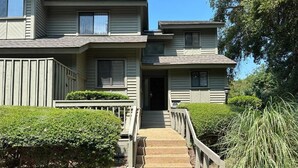A two-story building with a front entrance, a staircase, and a small porch area. - 3-bedroom 4 Beds condo in Shipyard Plantation, Hilton Head Island w/beach access (Hilton Head Island)