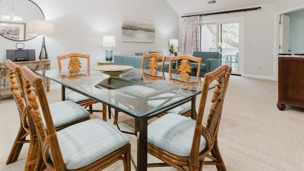 A dining area with a glass table, wicker chairs, and a modern lamp. - 3-bedroom 4 Beds condo in Shipyard Plantation, Hilton Head Island w/beach access (Hilton Head Island)
