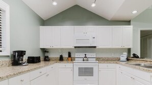A kitchen with white cabinets, a stove, a microwave, and a coffee maker. - 3-bedroom 4 Beds condo in Shipyard Plantation, Hilton Head Island w/beach access (Hilton Head Island)