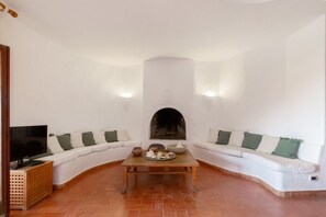 A living room with a fireplace, a sofa, a television, and a coffee table. - VILLA LAURA - Villasimius, where home and sea are one step apart (Villasimius)