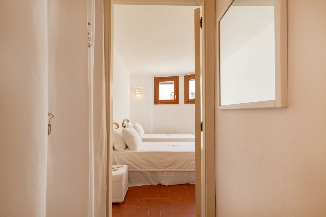 A bedroom with two beds, a small bedside table, and a mirror on the wall.