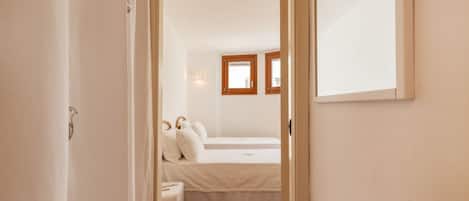 A bedroom with two beds, a small bedside table, and a mirror on the wall.