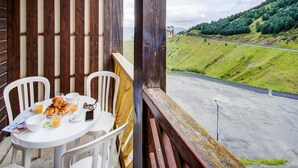 Un balcón con una mesa dispuesta para el desayuno, con vistas a un paisaje montañoso.