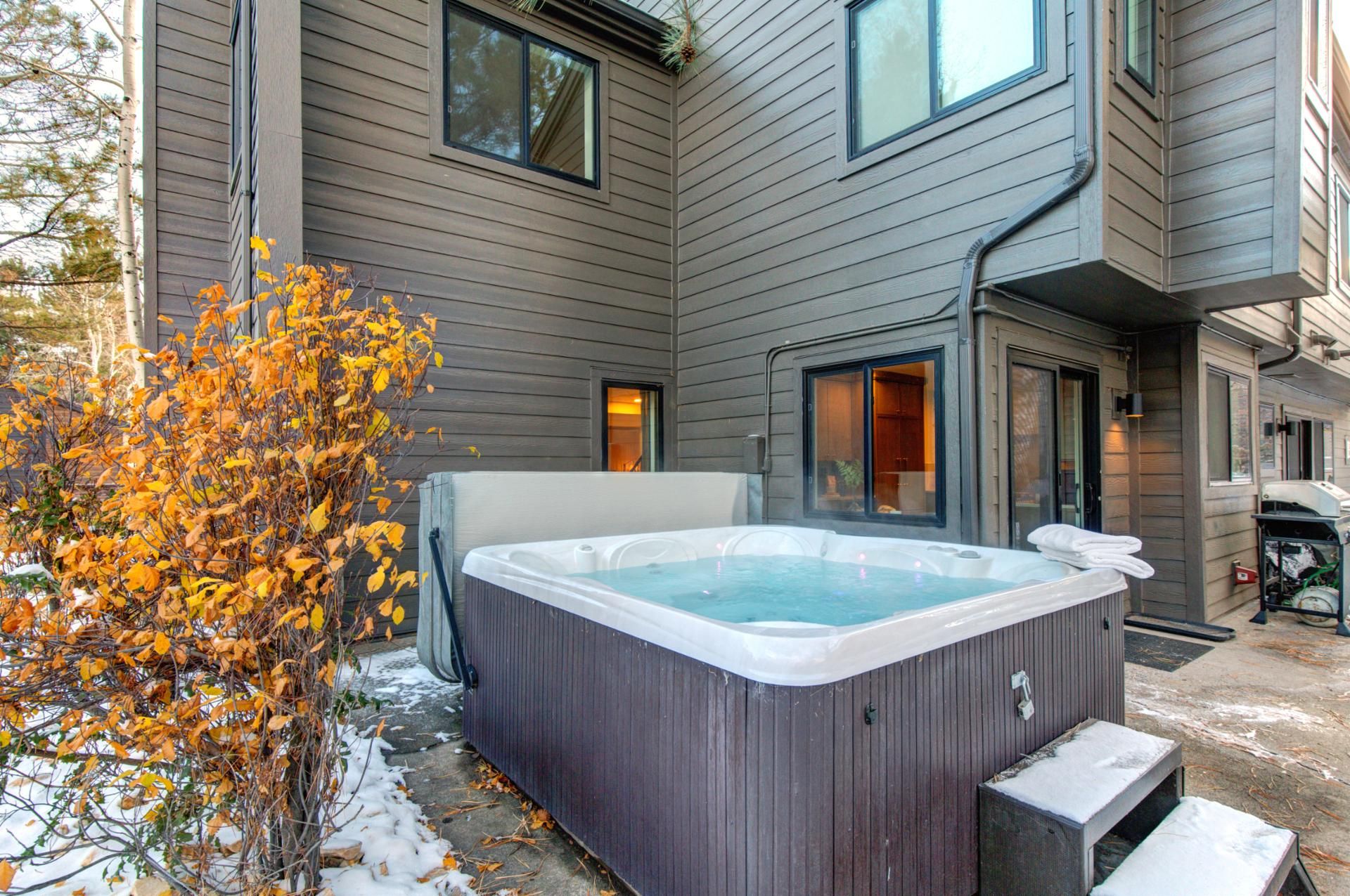 A hot tub in front of a house with a wooden exterior.