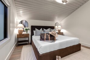 Quarto com uma cama grande, duas mesas de cabeceira, um espelho e uma janela.