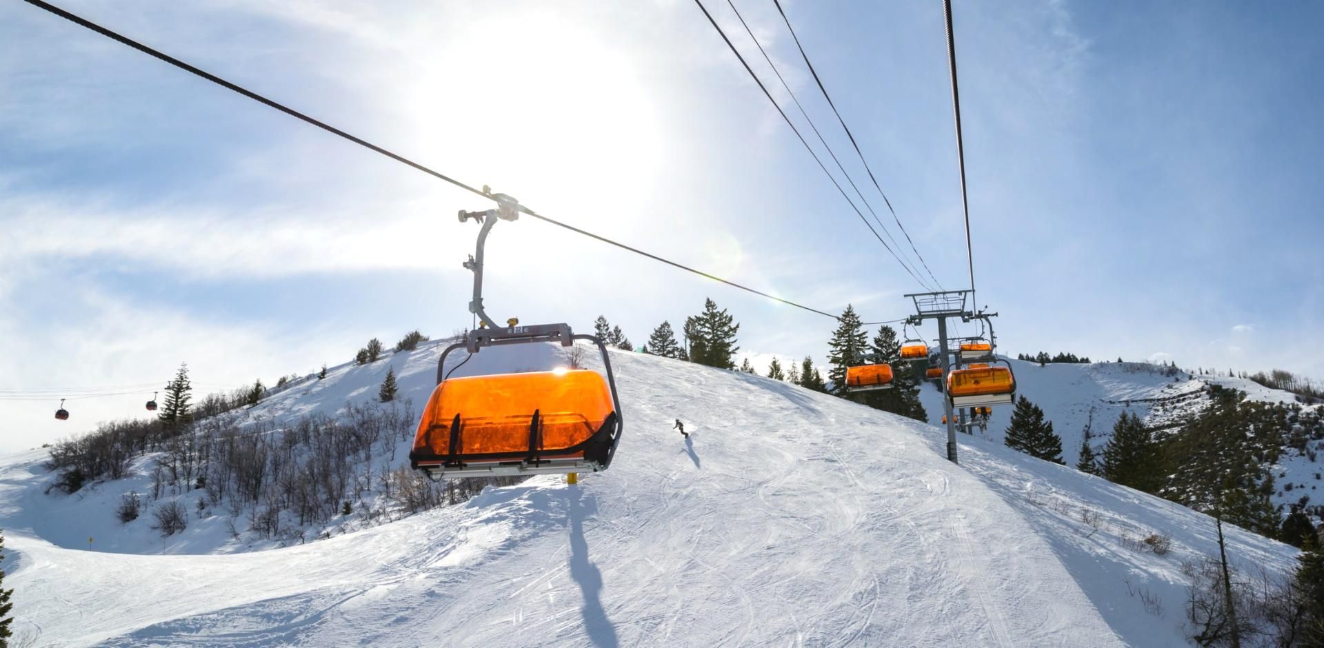 A ski lift with orange cabins on a snowy mountain slope.