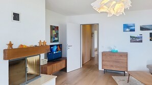 A modern living room with a fireplace, a television, a wooden cabinet, and a dining area. - Casa Rivapiana by Interhome (Muralto)