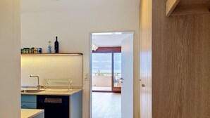 A modern kitchen with a built-in dishwasher, a wine bottle on the counter, and a view to the outside. - Casa Rivapiana by Interhome (Muralto)