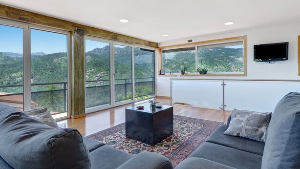 A modern living room with a large window, a flat-screen TV, and a cozy sofa. - Apartment 'Casa Do Lagar' with Lake View, Wi-Fi and Air Conditioning (Geres)