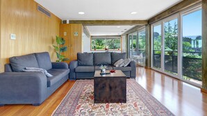A modern living room with a sectional sofa, a coffee table, and a large window offering a view of greenery. - Apartment 'Casa Do Lagar' with Lake View, Wi-Fi and Air Conditioning (Geres)