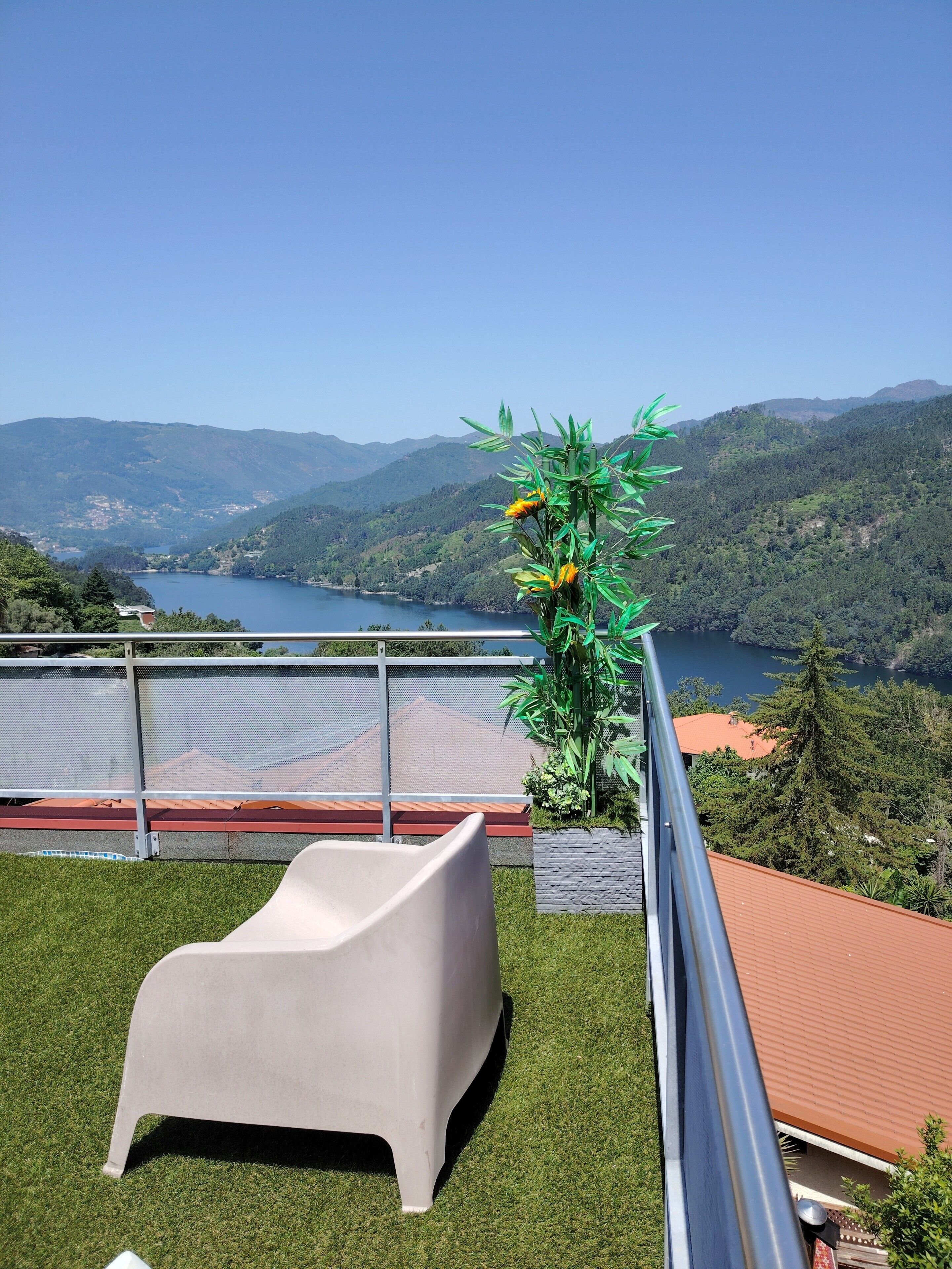 Un balcon avec une chaise, une plante et une vue sur un lac et des montagnes.
