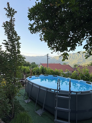 An outdoor swimming pool surrounded by greenery, with a view of mountains in the background. - Authentic MNE stone villa with renovated apartments - 10 min to Lake Skadar (Virpazar)