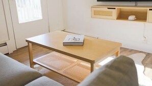 Una sala de estar con un sofá, una mesa de centro, una televisión y una estantería.