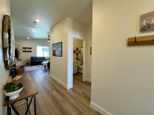 A modern interior with a wooden floor, a dining area with a table and chairs, a living room with a sofa, and a kitchen area. - Colorado Fun House (Fruita)